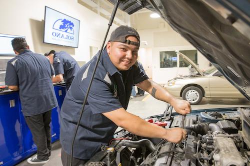 Automotive student working on a car engine.